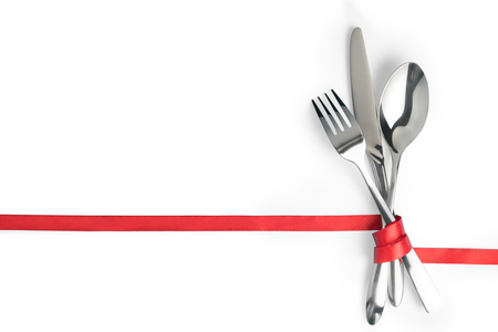 Fork, spoon and knife tied with a red ribbon. Isolated on whiteの写真素材