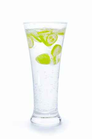 Small green citrus fruit slices into drinking glass full of water with splash and bubbles. Isolated on white, clipping path includedの写真素材
