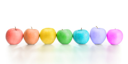 Row of different rainbow colored apples with reflection. Isolated on white, clipping path included. Creativity, diversity, arts and fantasy conceptの写真素材