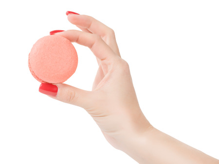 Woman hand holding pink round macaroon. Isolated on white, clipping path includedの写真素材