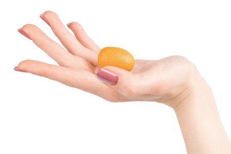 Woman hand with purple nail polish holding small orange kumquat on the palm.の写真素材