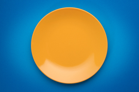 Empty yellow plate on blue background. Top viewの写真素材