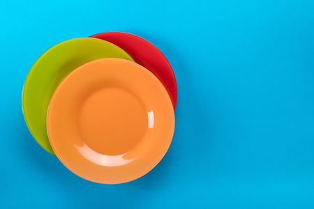 Empty bright colored plates on blue background top view with copy spaceの写真素材