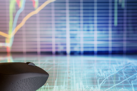 Computer mouse on futuristic display with defocused stock market graphs. Internet trading and modern business themeの写真素材
