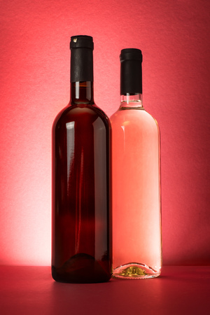 Red and white wine bottles on red backgroundの写真素材