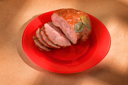 Sliced ham on a red plate. Food theme still life