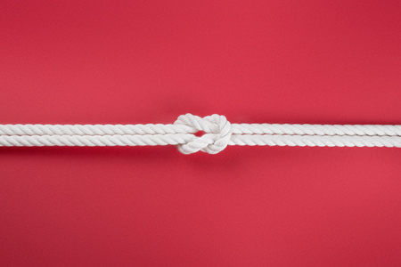 White ship ropes connected by reef knot. On red backgroundの写真素材