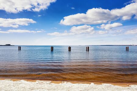 Bright colored sea landscape at sunny day. Clouds, coastal line and old pillars in the seaの写真素材