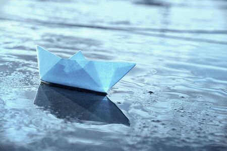 Lonely blue paper boat in shallow water. Blue toned image. の写真素材