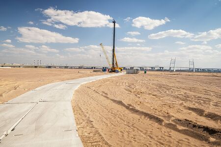 Site ready for building construction. Panoramic landscape with sand, drilling machine and distant city horizonの写真素材