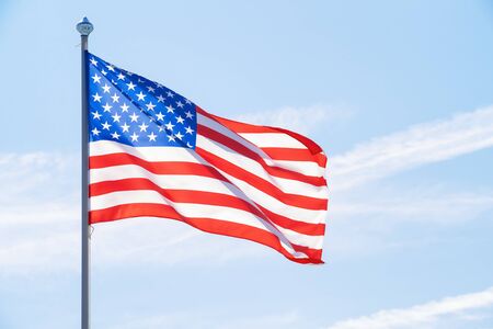 American flag on flagpole against blue cloudy skyの写真素材