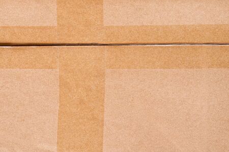 Cardboard box crossed by adhesive tape close up. Texture and backgroundの写真素材