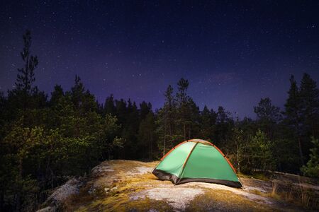 Illuminated tent at night in the northern forest under starry sky. Long exposureの写真素材