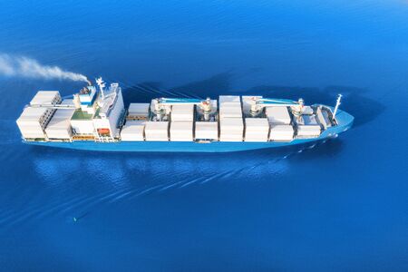 Large full loaded container ship with cranes sailing bright blue sea. Aerial viewの写真素材