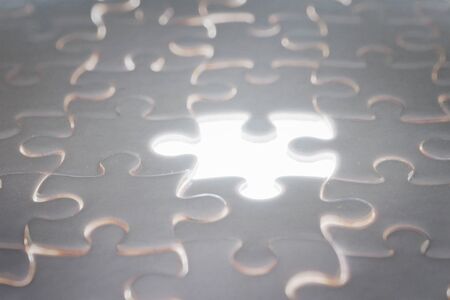 White blank jigsaw puzzle with blank illuminated piece. Selective focusの写真素材