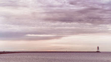 Old lone lighthouse at sunset sea. Panoramic warm toned imageの写真素材