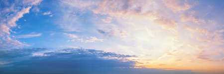 Pastel colored sunset sky long panoramic view. Sun into clouds at golden hour