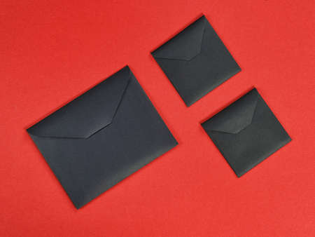 Three black cardboard envelope on red background. Top view, flat layの写真素材