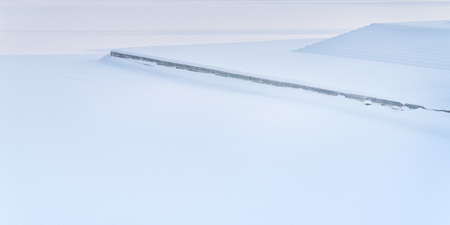 Snow-covered embankment, granite steps and ice surface. Abstract winter landscape with copy spaceの写真素材