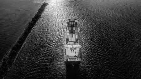 Large full loaded container ship sailing sea near the coast. Aerial view, black and white hdr imageの写真素材