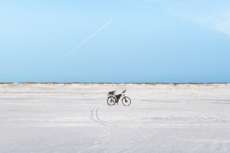 Lone electric bike on snow plain under blue sky. Abstract winter theme imageの写真素材