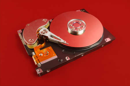 Disassembled hard drive close up with plates visible on red background