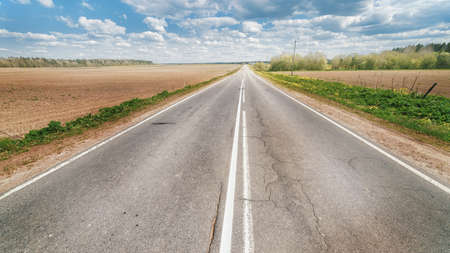 Endless country road to the horizon under cloudy sky. First person view view cinematic panoramic viewの写真素材
