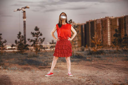 A girl in red with a mirror mask covering her face against industrial urban landscape. abstract surreal portraitの写真素材