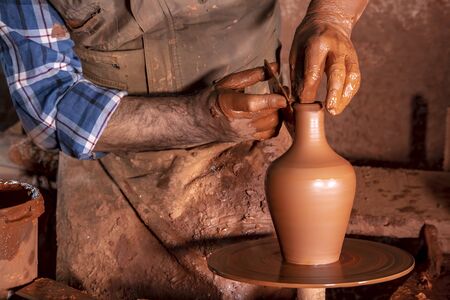 Professional potter making bowl in pottery workshop, studio.