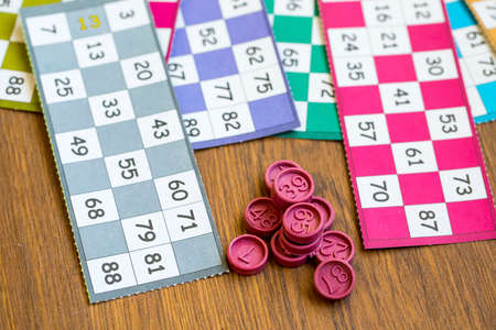 Colorful bingo game cards and numbers on white background, close up, isolated.