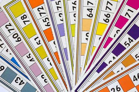 Colorful bingo game cards and numbers on white background, close up, isolated.