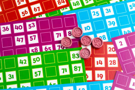 Colorful bingo game cards and numbers on white background, close up, isolated.