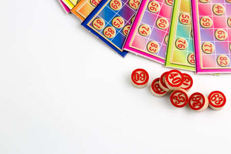 Colorful bingo game cards and numbers on white background, close up, isolated.