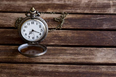 An antique pocket watch lies on a wooden table top viewの写真素材