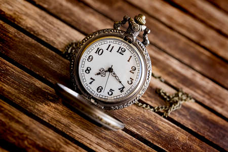 An antique pocket watch lies on a wooden table top viewの写真素材