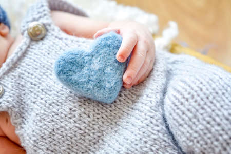 In the hands of the baby, blue heart, symbol of love.の写真素材