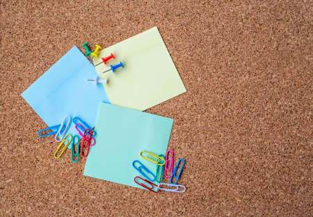 Cork board with several colorful blank notes with pins