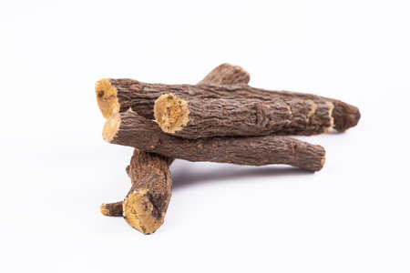 Macro closeup of a traditional sweet heap pile of Liquorice licorice wooden wood roots sticks isolated on whiteの写真素材