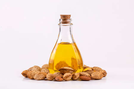 Almond oil in a glass bottle on a white background with almondsの写真素材