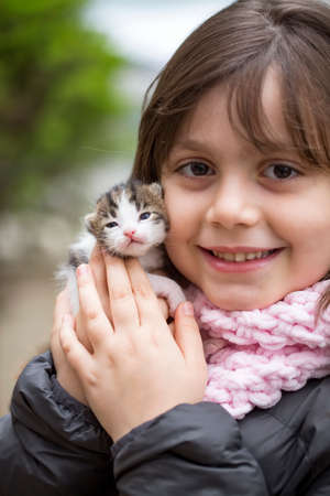 Cute little girl holding a kitten in her hands. Selective focus.の写真素材
