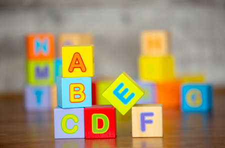 Colorful wooden toy cubes with letters A, B, C, D on wooden tableの写真素材
