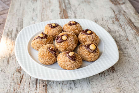 Homemade coconut cookies with chocolate and nuts on a white plate.の写真素材