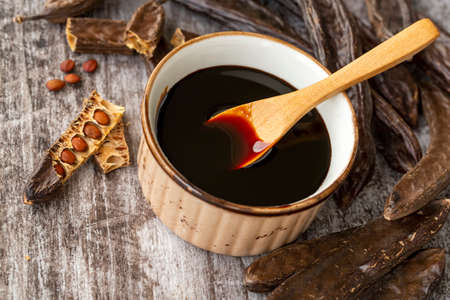 Carob pods and soy sauce in a bowl on a wooden backgroundの写真素材