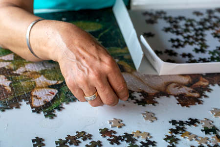 Close-up of the hands of an elderly woman completing a puzzleの写真素材