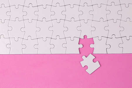 Missing jigsaw puzzle pieces. Business concept. Fragment of a folded white jigsaw puzzle and a pile of uncombed puzzle elements againstの写真素材