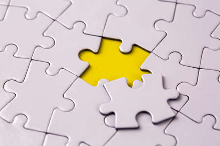 Missing jigsaw puzzle pieces. Business concept. Fragment of a folded white jigsaw puzzle and a pile of uncombed puzzle elements againstの写真素材