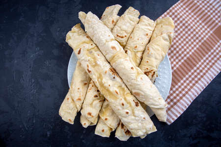 Homemade thin pancakes with cottage cheese on a plate on a black backgroundの写真素材