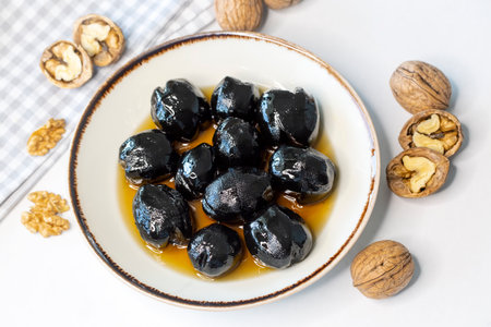 Black olives with honey and walnuts on a white background.の写真素材