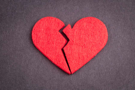 Broken red heart on black background. Symbol of broken heart.の写真素材
