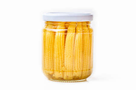 Pickled young baby corn cobs in jar isolated on white background.の写真素材